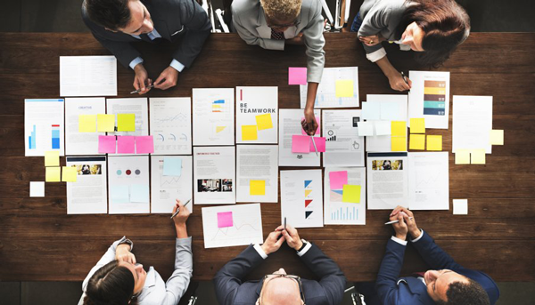 a team of people sitting at a table looking at paperwork