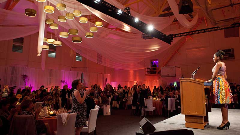 a woman speaking in front of people in the office venue