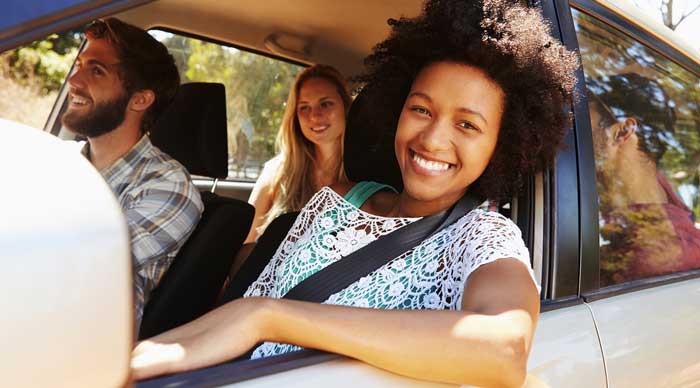 a woman smiling together with other people inside the car