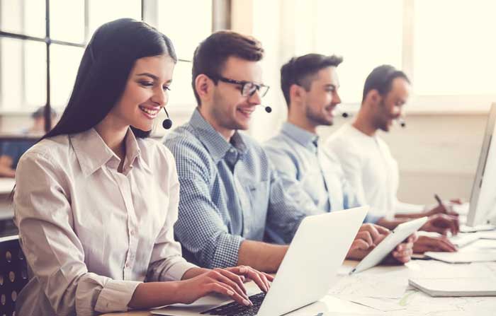 4 people wearing headphone staring at their laptop communicating to customers