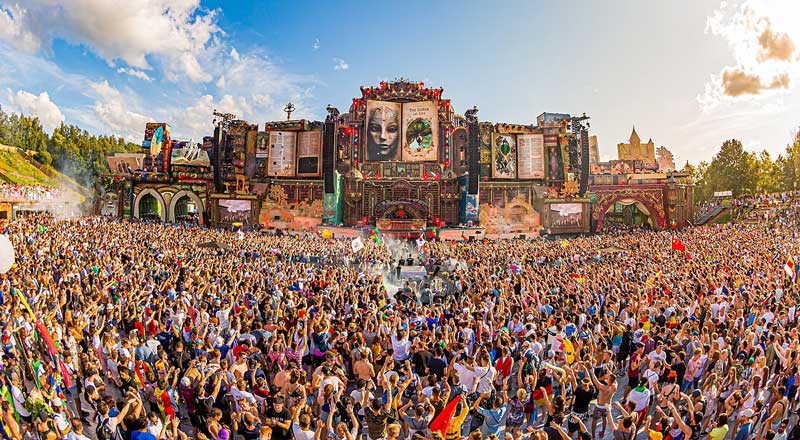 a large crowd of people waving their arms at a music festival