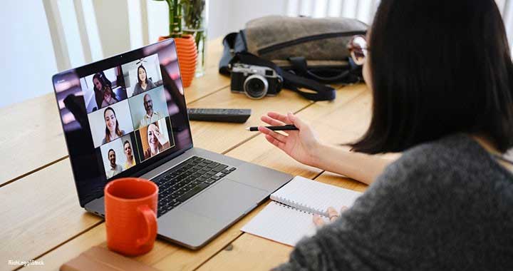 A person looking her computer talking to other people.