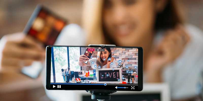 A woman live streaming on her phone showing makeup.