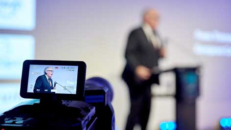 man being filmed on stage with a purple background