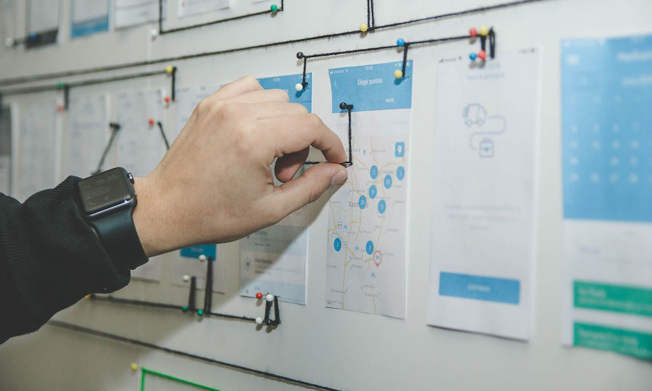 man pinning a tac on a board with papers