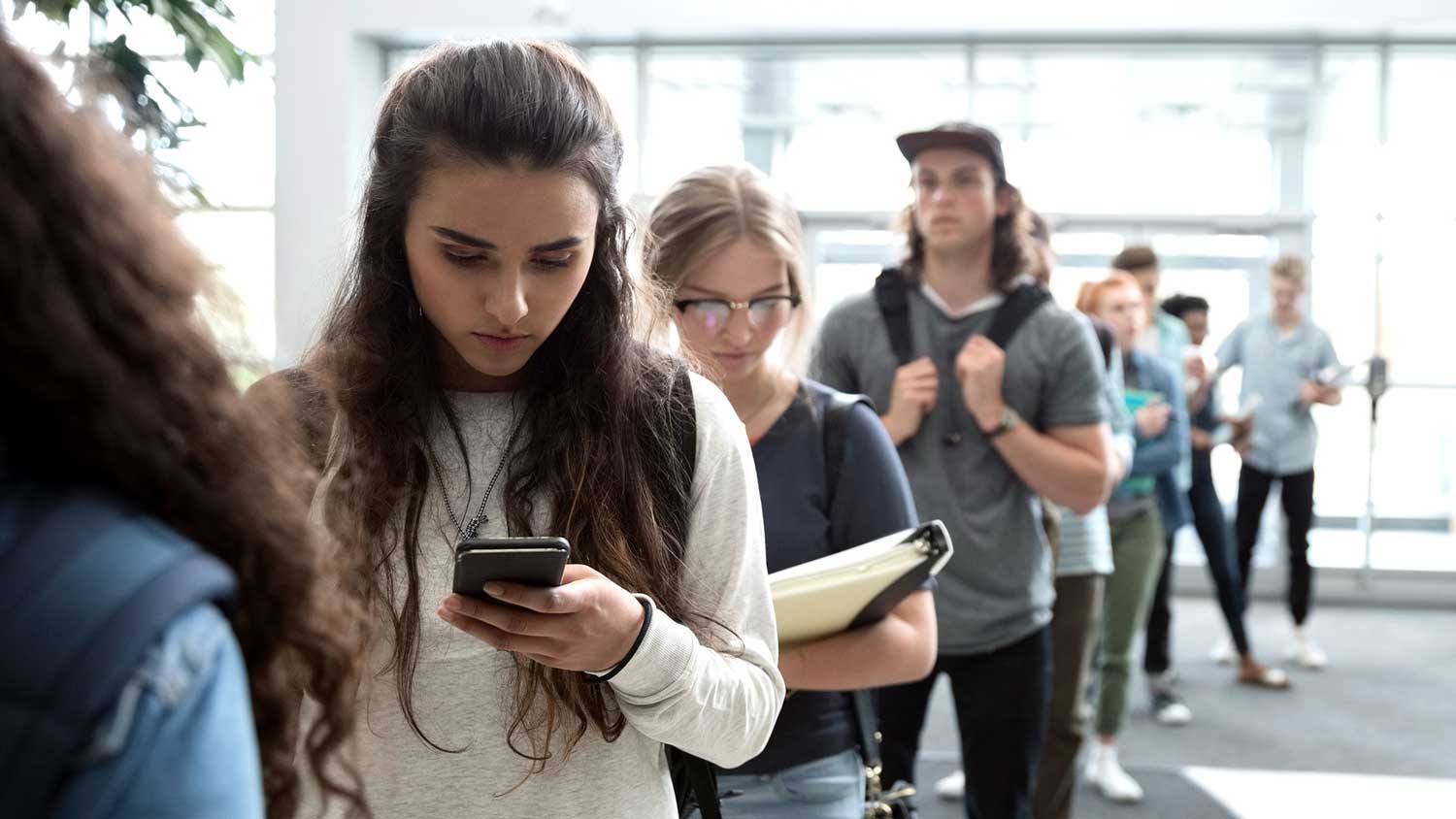 a-girl-looking-at-her-phone-waiting-in-line