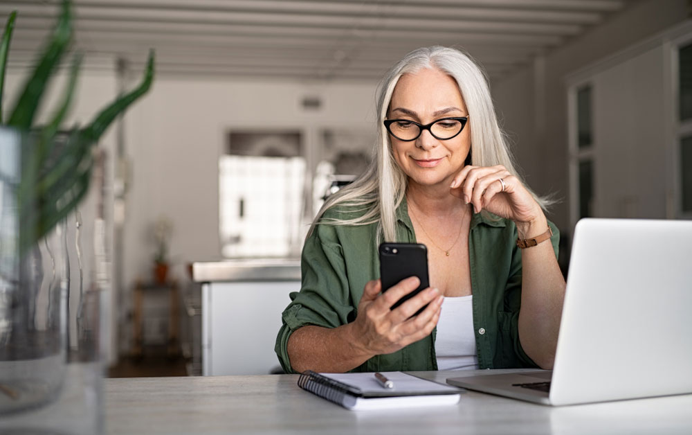 a-woman-with-white-hair-and-a-green-jacket-looking-at-her-phone