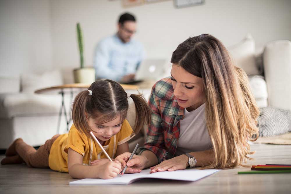 a mom working with her student from home on homework on the ground