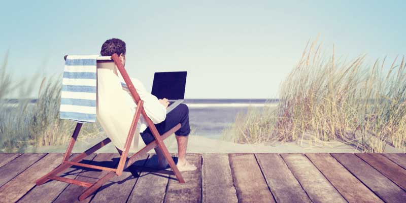 a-man-typing-on-his-computer-at-the-beach